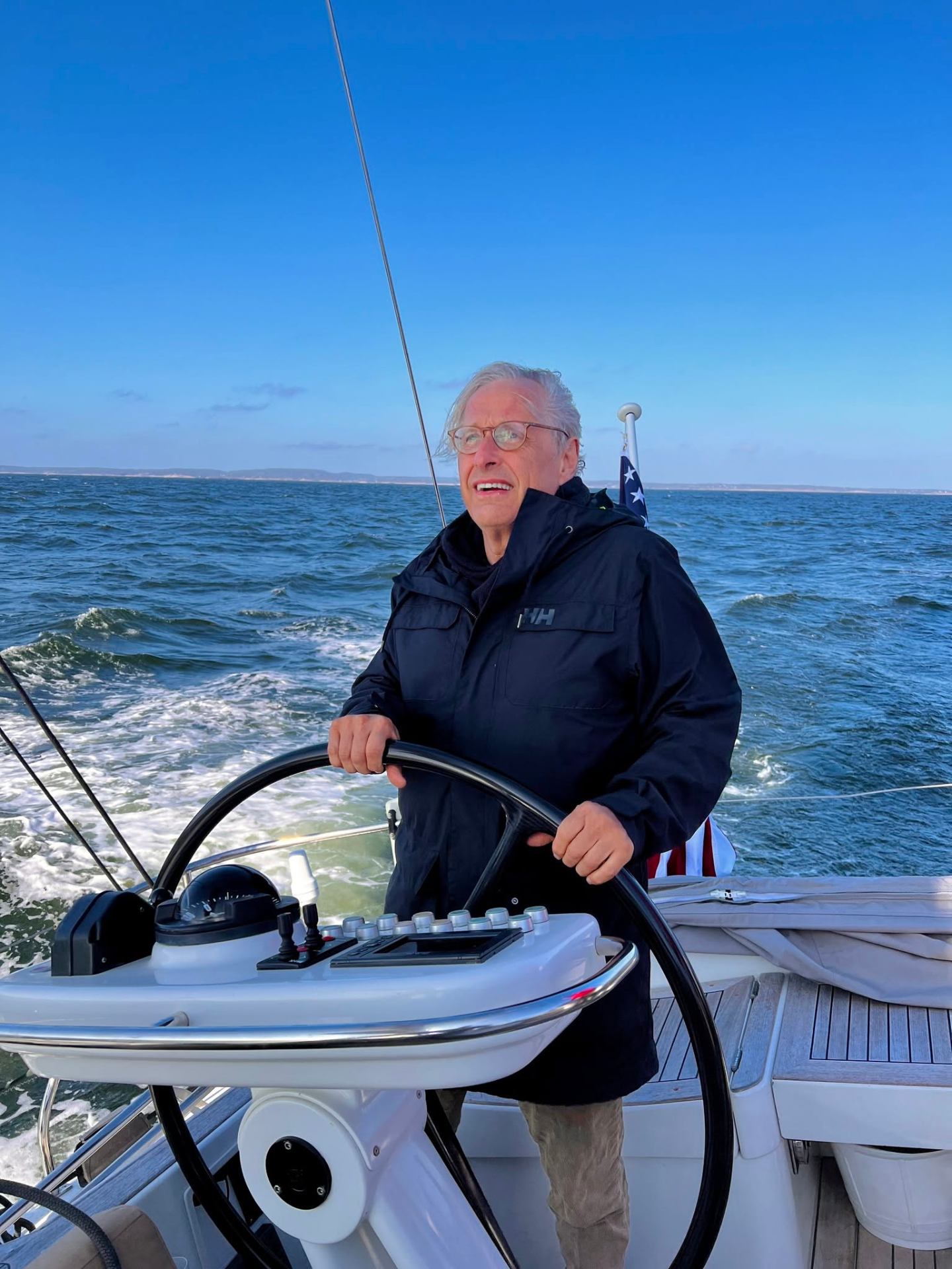 Pierre at the helm of a modern sailboat on open water.